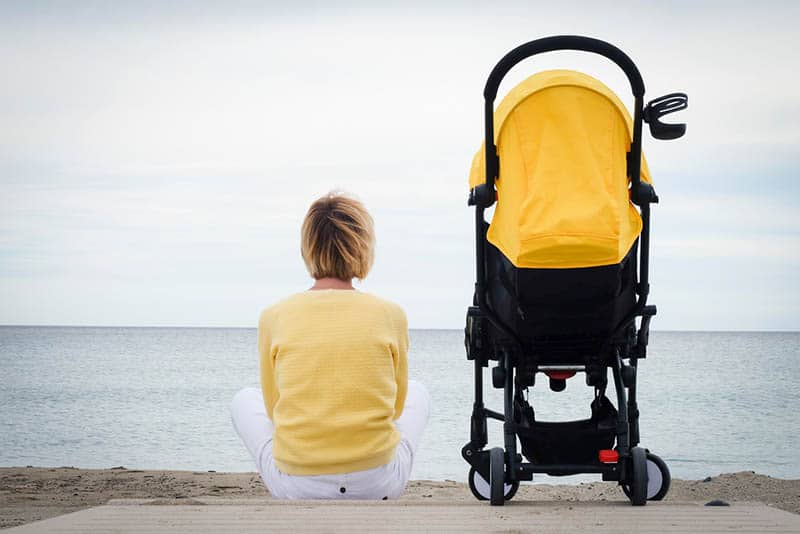 woman sitting on the beach with baby in a stroller