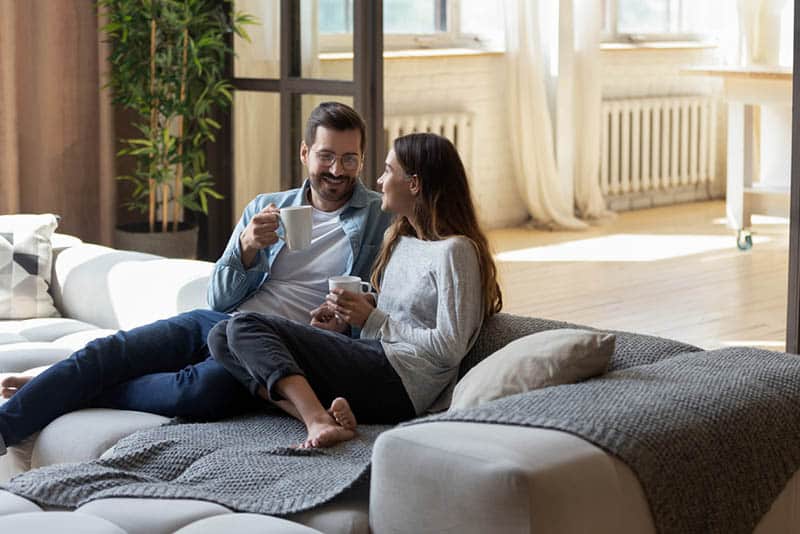 young couple drinking coffee on the huge couch at home