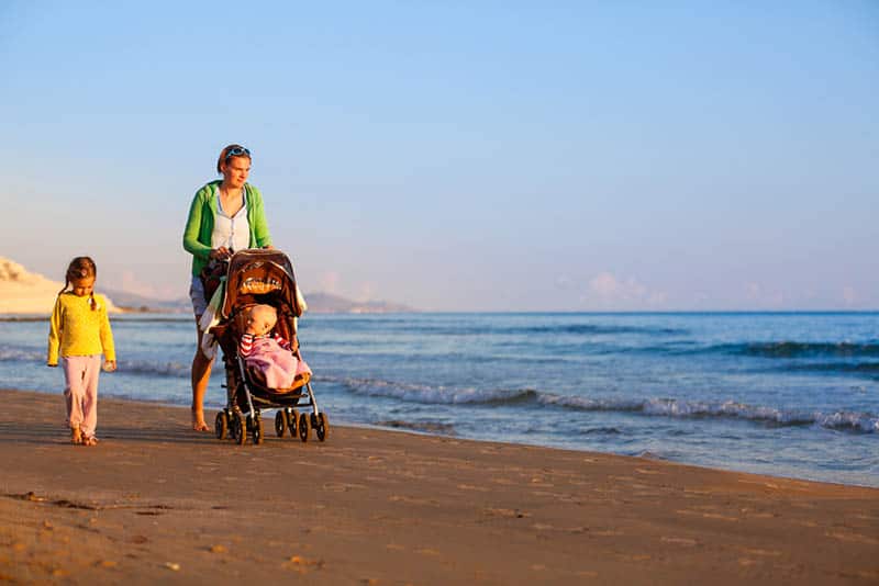 young mother walking with kids on the beach