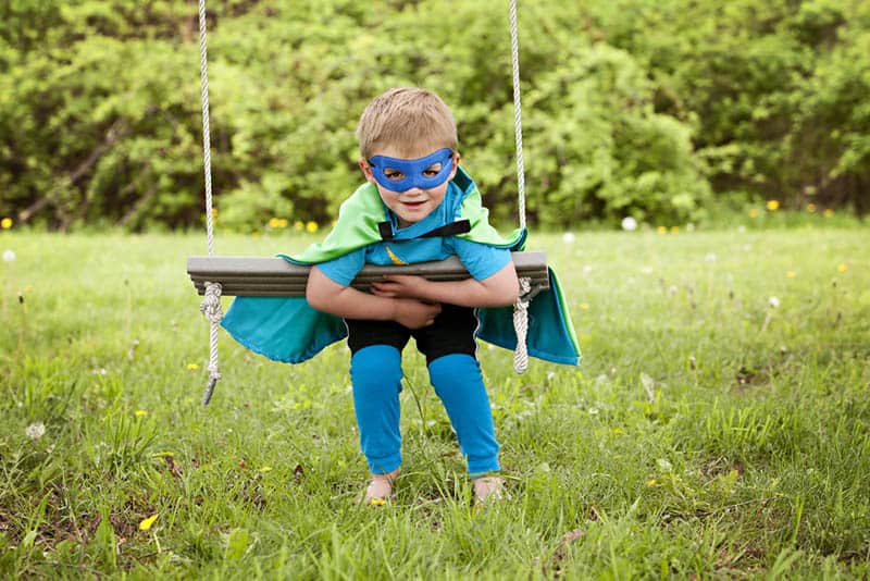 Adorable little boy dressed in a cape and mask playing superhero