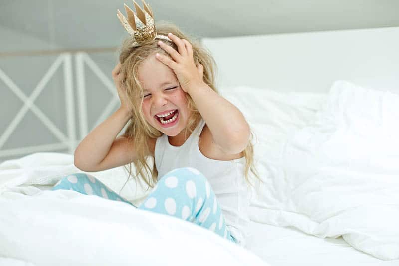 Adorable little girl awaked up in her bed with crown on head