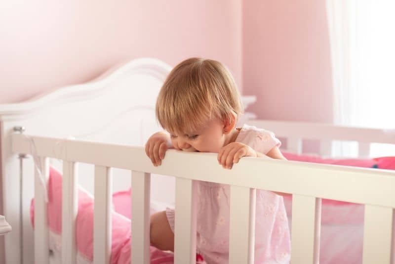 two year old toddler standing in her crib