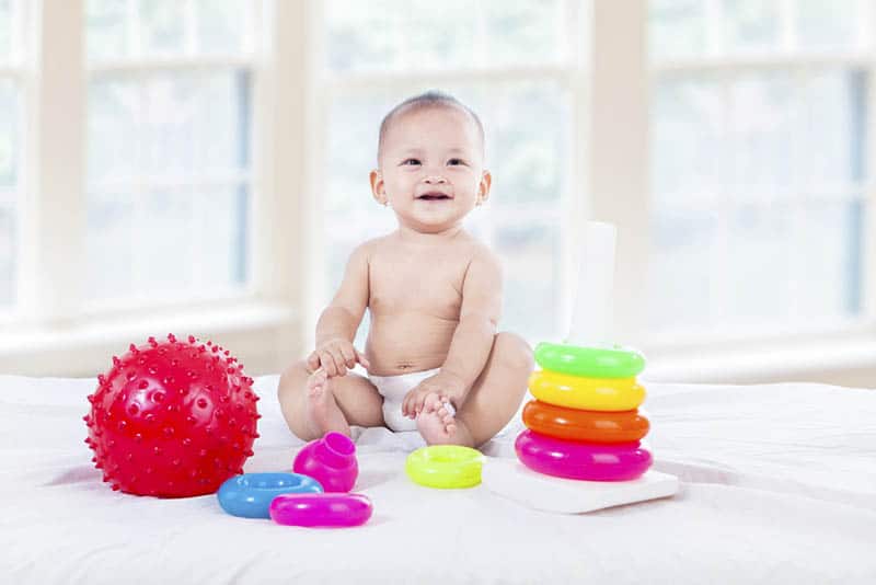 Cute baby with colorful toys at home