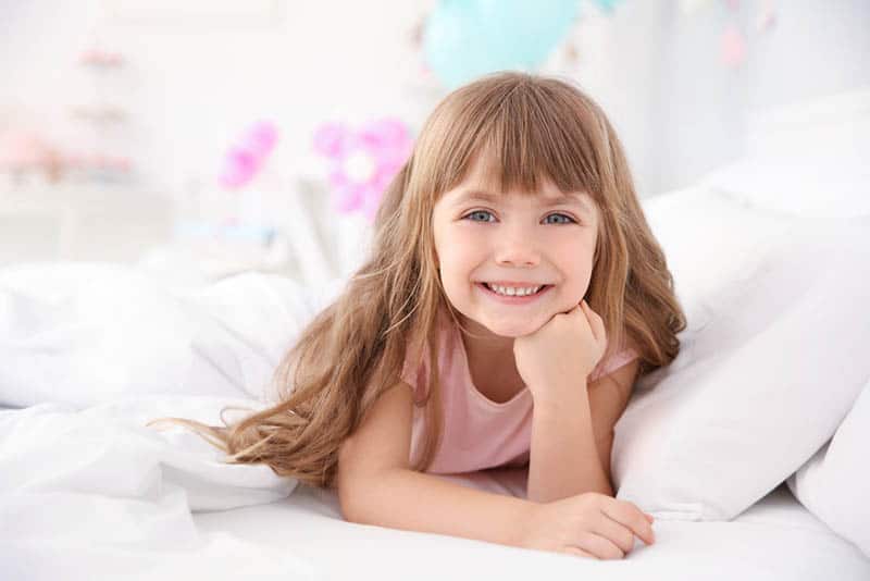 Cute little girl lying in bed at home