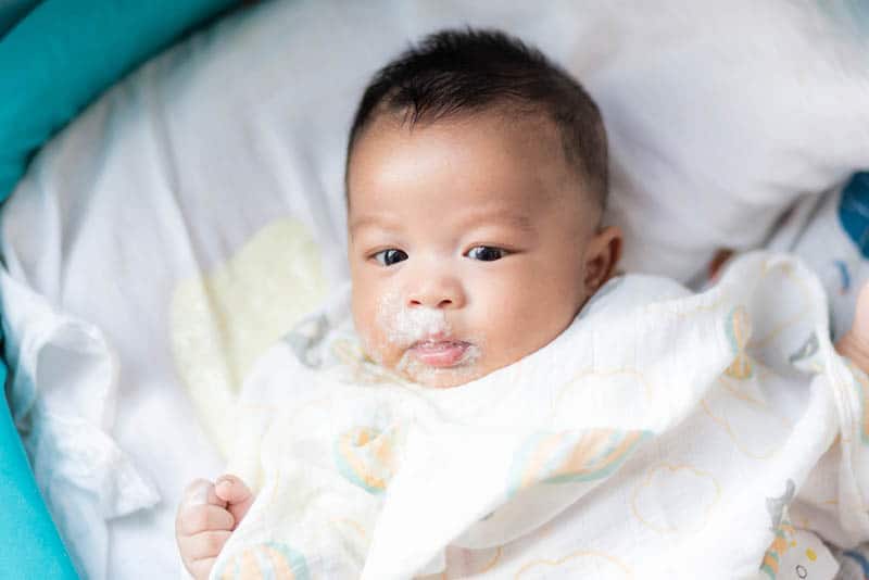 Infant baby boy vomit after eating milk on bed
