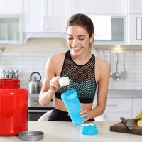 young woman preparing a pre workout drink in the kitchen before exercising
