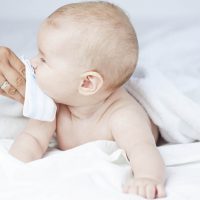 mother wiping milk coming out of the baby's nose with a handkerchief