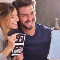 happy couple making a pregnancy announcement to parents with an ultrasound photo of their baby