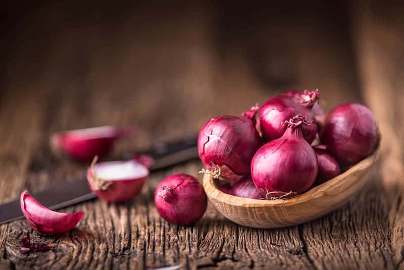 Red onions on very old oak wooden board