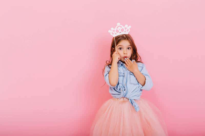 Surprised pretty young girl in tulle skirt with crown