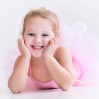 little girl wearing an elegant ballerina outfit and smiling at the camera
