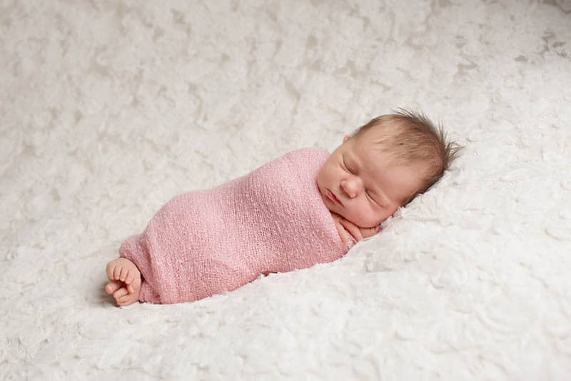 adorable baby girl sleeping swaddled in the pink cloth