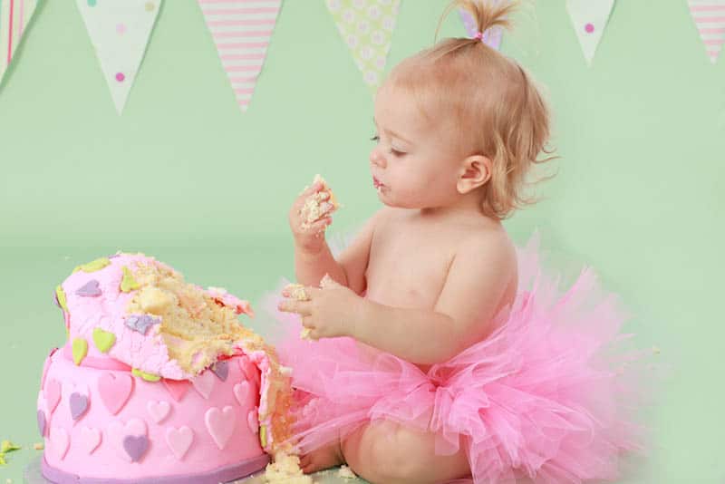 adorable baby girl wearing pink tutu skirt eating her birthday cake