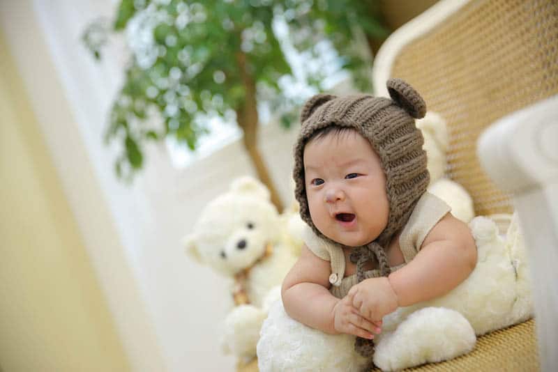 adorable baby wearing teddy hat on the floor