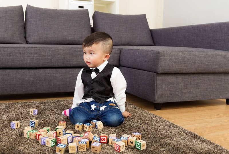 adorable little boy playing with wooden blocks on the floor
