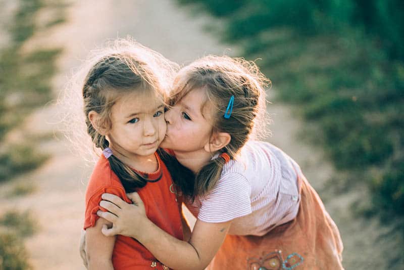 adorable little girl kissing her sister outdoor