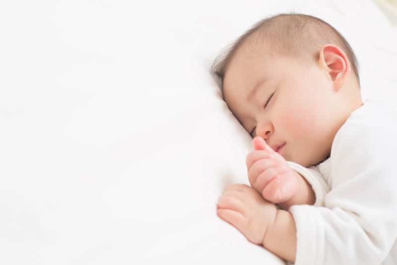 baby boy sleeping tight on white sheet