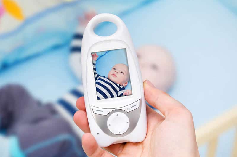 baby monitor in hand while baby is in the crib