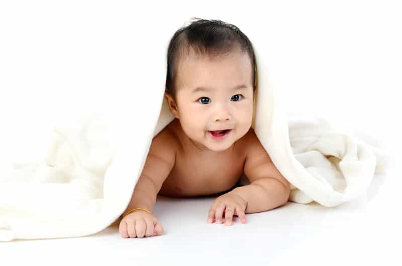 beautiful asian baby boy crawling under the blanket