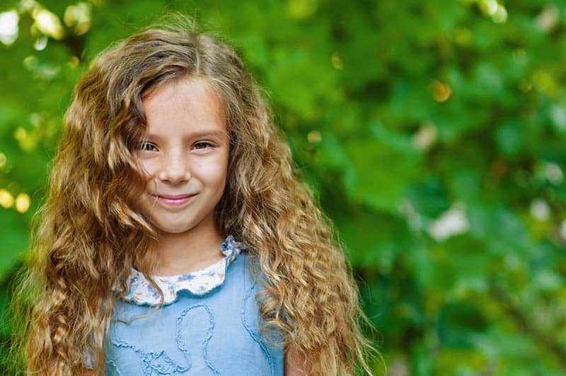 beautiful little girl with curly hair posing outdoor