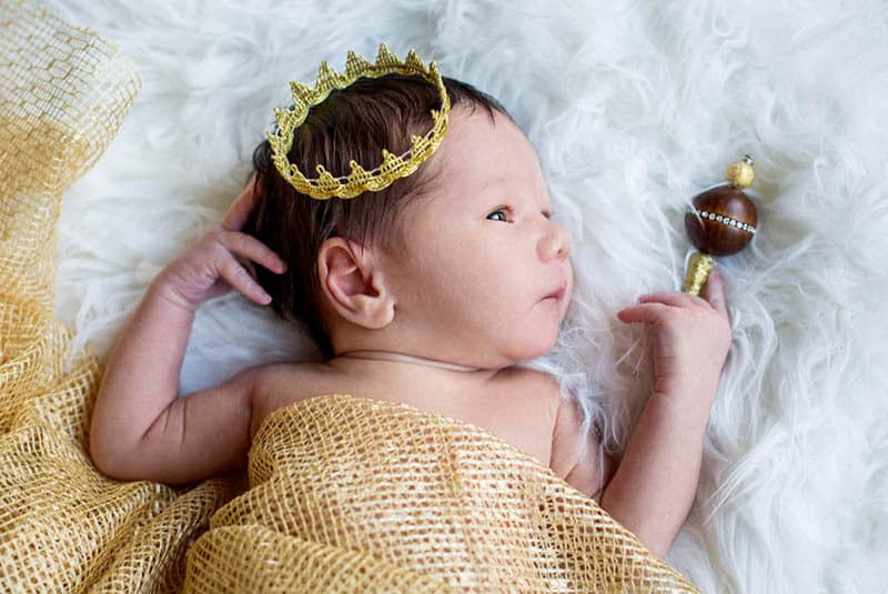 cute baby boy with golden crown lying in bed