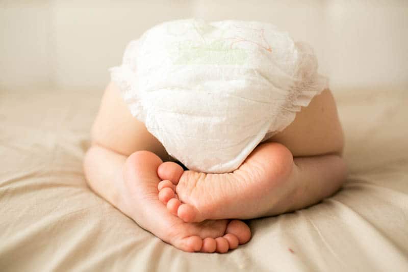 cute baby wearing diapers while lying on the bed