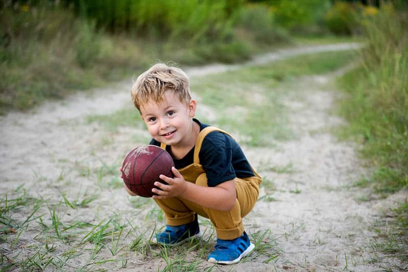 cute little boy holding a ball on the sand