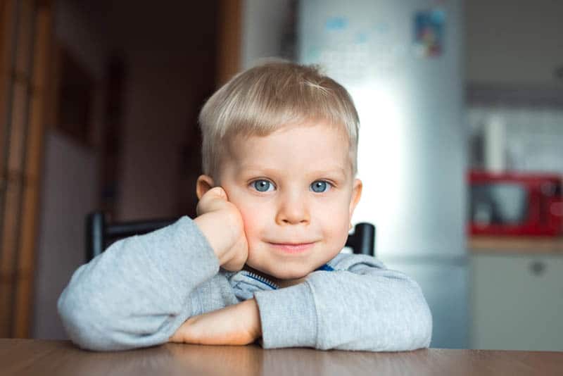cute little boy sitting on chair in the kitchen