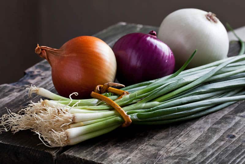 different colorful onions on the wooden table