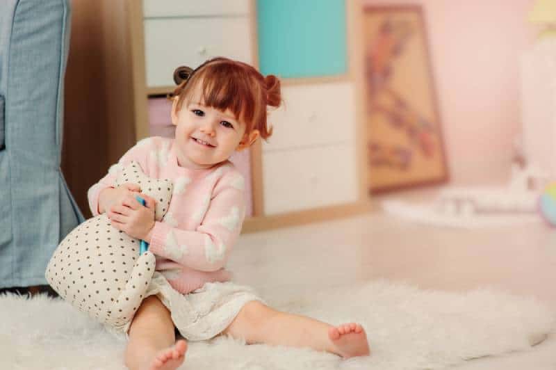 little girl hugging her toy on the floor