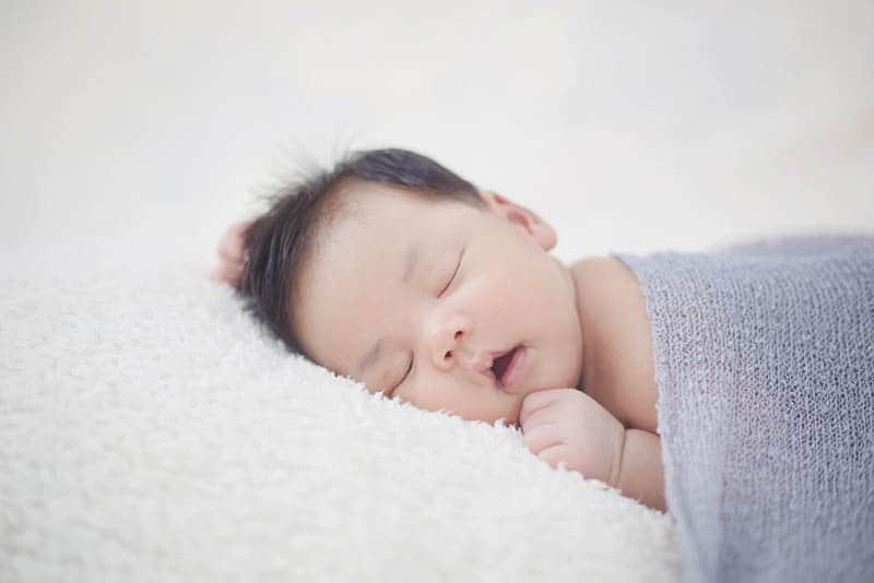 lovely newborn baby boy sleeping covered with blanket