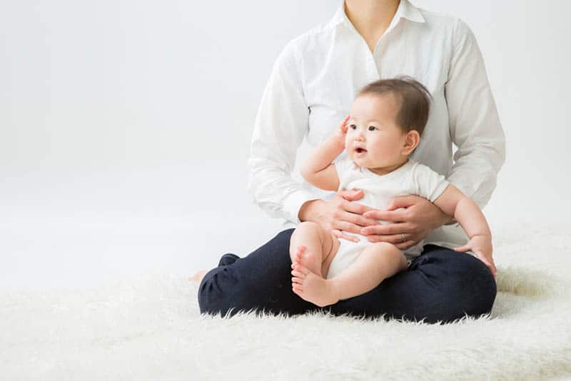 mother holding her baby boy on the white carpet