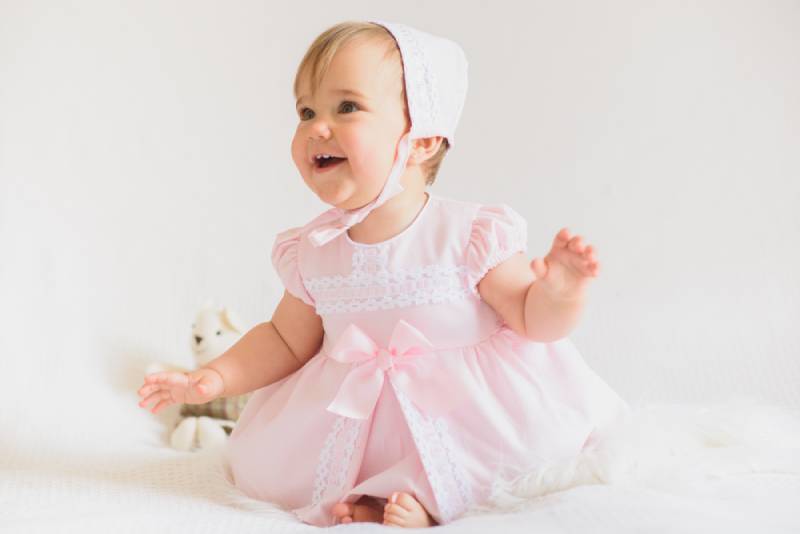 smiling baby girl wearing a dress and hat
