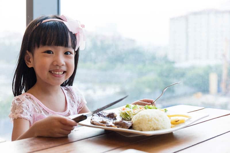 smiling little girl posing with food on the plate