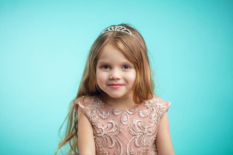 sweet little girl wearing a crown and a princess dress and smiling