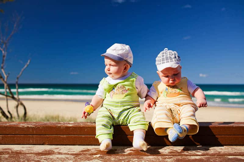 twin babies sitting outdoor on the beach