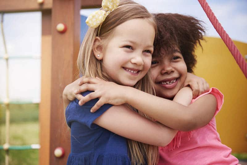 two adorable little girls hugging outdoor