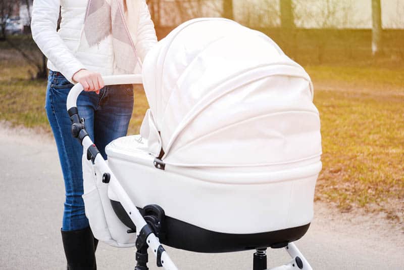 woman pushing baby strollers with white canopy