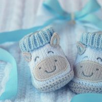 blue knitted baby shoes for a first grandchild announcement