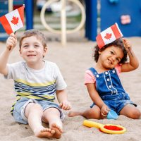 adorable little boy and girl holding canadian flags on the beach