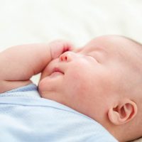 newborn baby scratching his face on the bed