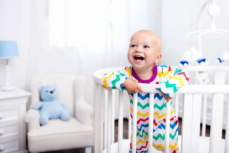 Cute laughing baby standing in bed after nap time