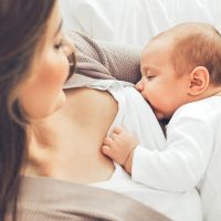 mother breastfeeding her cute baby in the bed
