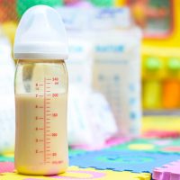 a bottle of breast milk in front of other baby items