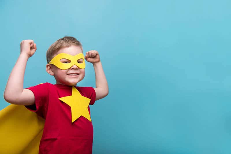 Little child dressed up as a superhero with yellow cloak and star