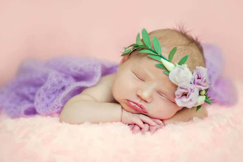 Newborn baby girl posing in tutu skirt and flower head band