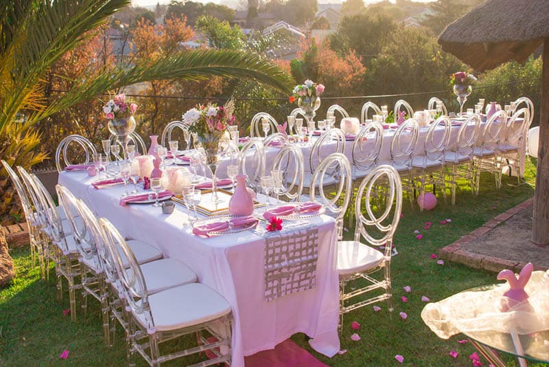 Party tables and chairs seating with pink decorations for a baby shower