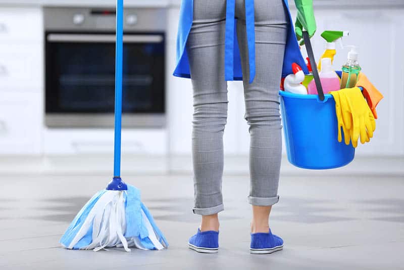 Woman with floor mop and bucket with washing fluids