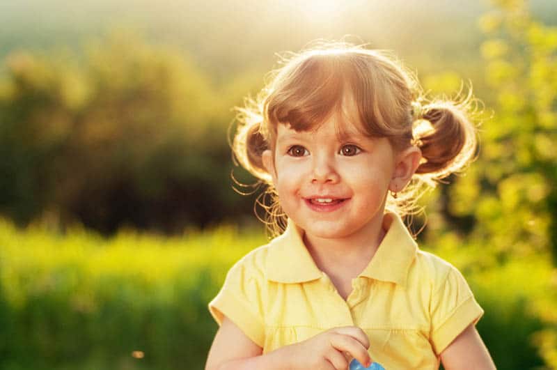 adorable little girl standing in sunlight outdoor