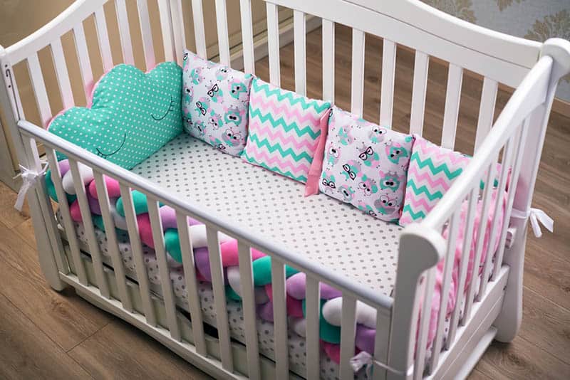 baby crib with colorful rail and pillows